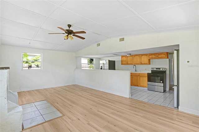 unfurnished living room featuring sink, ceiling fan, light tile patterned floors, and vaulted ceiling