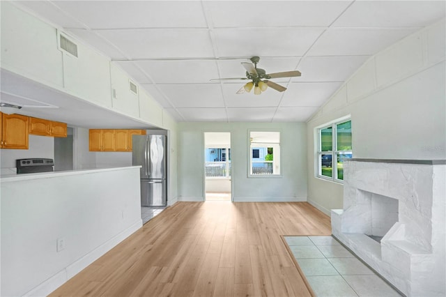 unfurnished living room with ceiling fan, a fireplace, vaulted ceiling, and light hardwood / wood-style floors