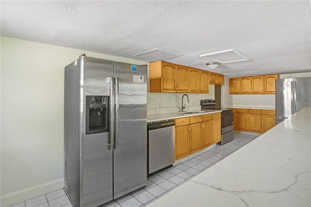 kitchen with sink, appliances with stainless steel finishes, light stone counters, a textured ceiling, and light tile patterned floors