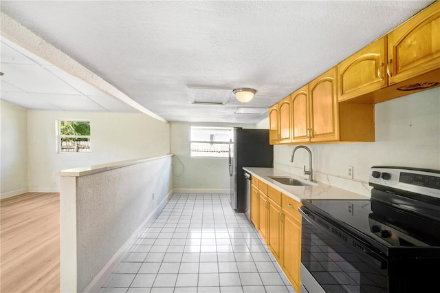 kitchen with appliances with stainless steel finishes, light hardwood / wood-style floors, a textured ceiling, and sink