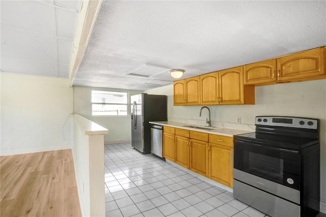 kitchen with appliances with stainless steel finishes, light hardwood / wood-style flooring, a textured ceiling, and sink