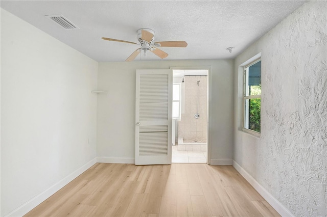 empty room featuring light wood-type flooring, ceiling fan, and a textured ceiling