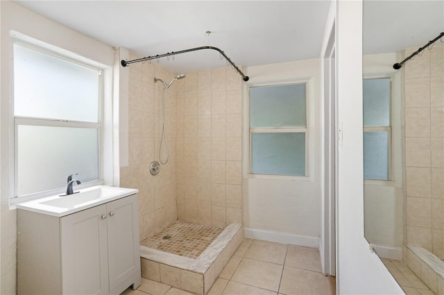 bathroom featuring tile patterned floors, a tile shower, and vanity