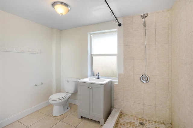 bathroom featuring tile patterned flooring, toilet, a tile shower, and vanity