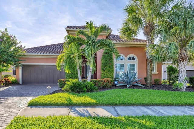 mediterranean / spanish-style home featuring a garage, a tiled roof, decorative driveway, and stucco siding