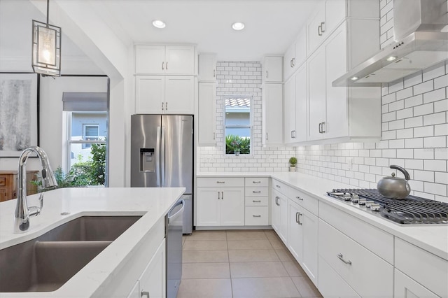 kitchen featuring wall chimney exhaust hood, tasteful backsplash, white cabinets, sink, and light tile patterned flooring