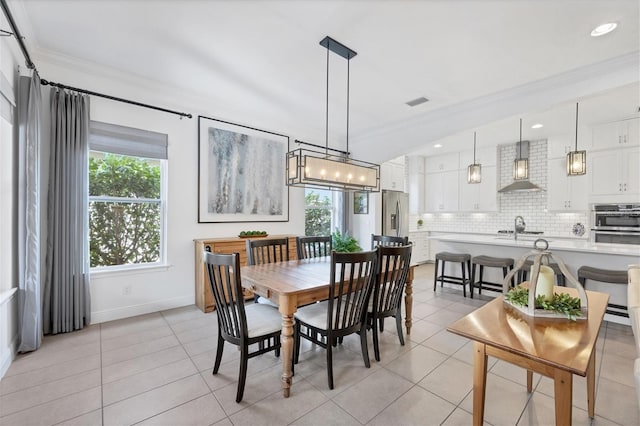 dining space featuring light tile patterned flooring, sink, and ornamental molding