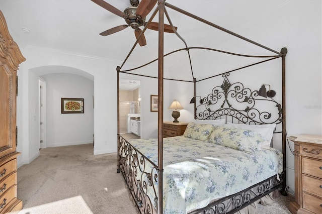 carpeted bedroom featuring ceiling fan, ensuite bath, and crown molding