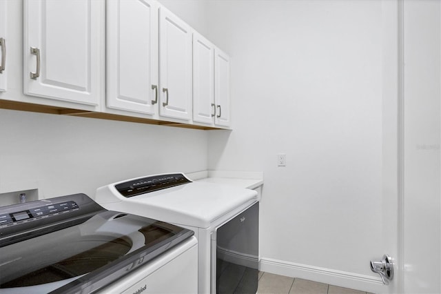 washroom featuring light tile patterned floors, washer and clothes dryer, and cabinets