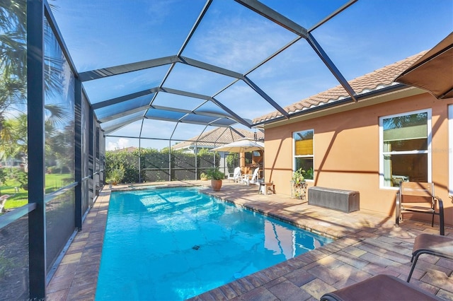 view of pool with glass enclosure and a patio