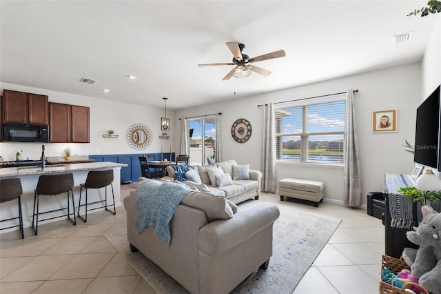 living room with sink, light tile patterned floors, and ceiling fan