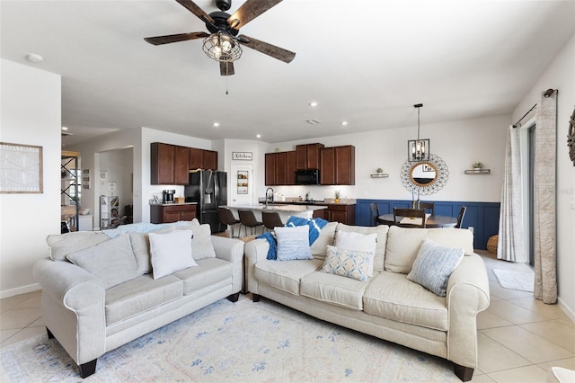 tiled living room with ceiling fan with notable chandelier and sink