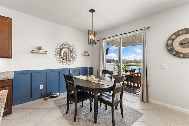 tiled dining room featuring a notable chandelier and a water view