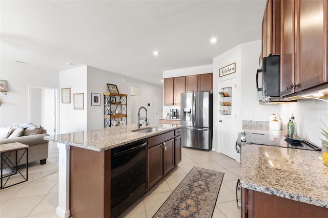 kitchen featuring light stone countertops, black appliances, light tile patterned floors, an island with sink, and sink