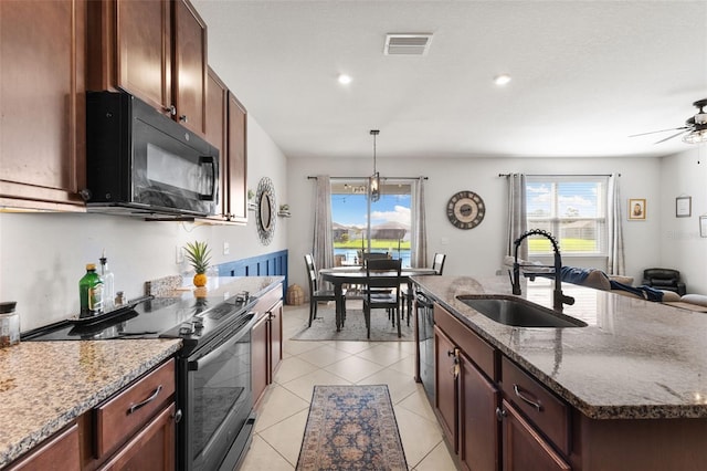 kitchen featuring ceiling fan with notable chandelier, light tile patterned floors, stainless steel appliances, sink, and stone countertops