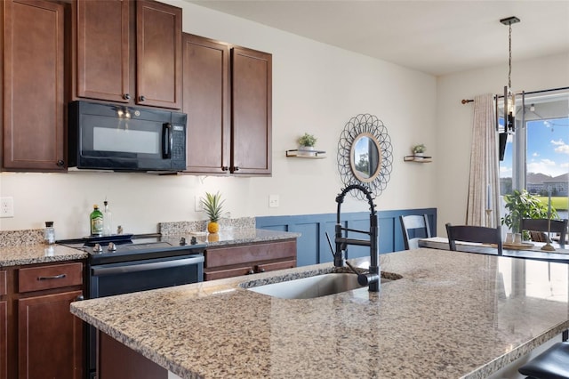 kitchen featuring light stone countertops, a kitchen bar, hanging light fixtures, sink, and stainless steel range with electric stovetop