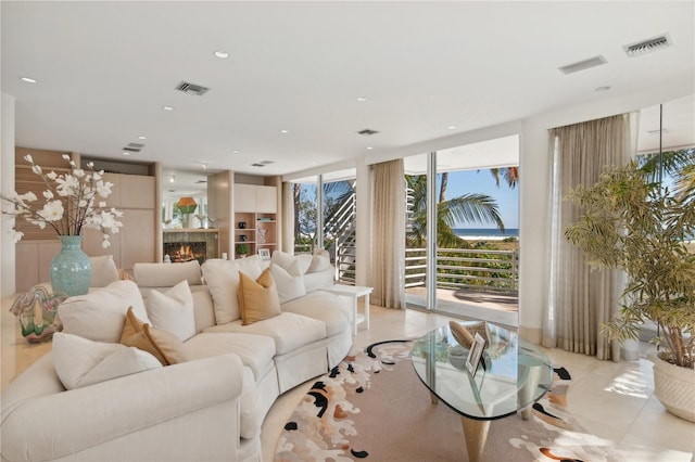 living area with a warm lit fireplace, floor to ceiling windows, visible vents, and recessed lighting