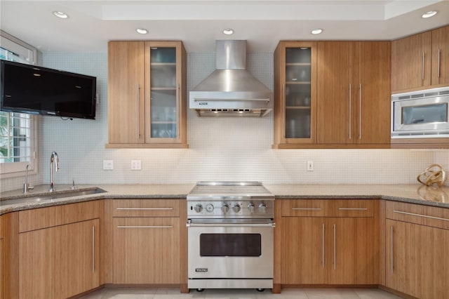 kitchen featuring tasteful backsplash, appliances with stainless steel finishes, a sink, light stone countertops, and wall chimney exhaust hood