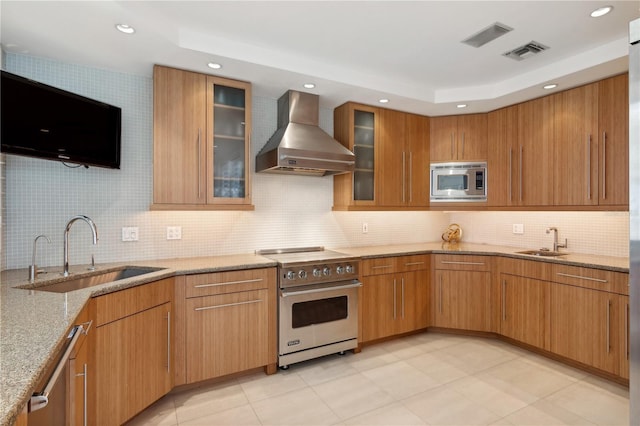 648 Beach Rd, Sarasota, FL 34242 - kitchen featuring stainless steel appliances, wall chimney range hood, a sink, light stone countertops, and recessed lighting
