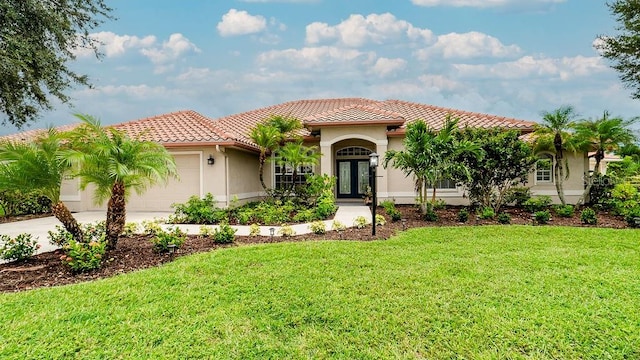 mediterranean / spanish home featuring a front lawn and a garage