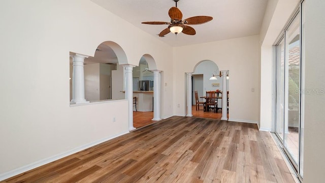 empty room with ceiling fan, light hardwood / wood-style flooring, and decorative columns