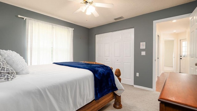 carpeted bedroom featuring ceiling fan and a closet