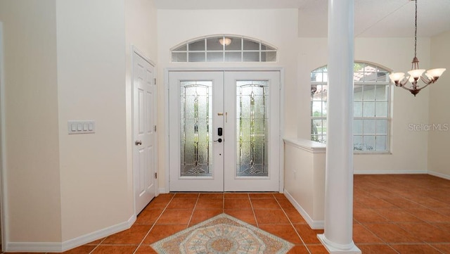 foyer featuring an inviting chandelier, tile patterned flooring, french doors, and ornate columns