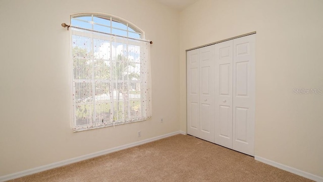 unfurnished bedroom featuring light carpet and a closet