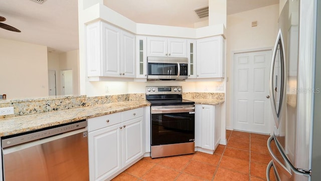 kitchen with ceiling fan, light stone counters, light tile patterned floors, white cabinetry, and stainless steel appliances