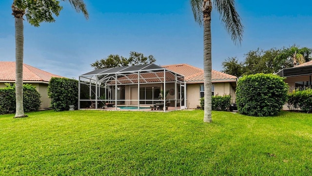 back of property featuring glass enclosure and a yard