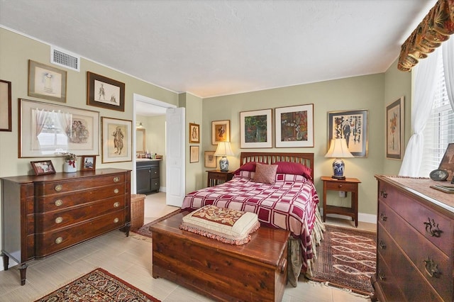 bedroom with connected bathroom, visible vents, and baseboards