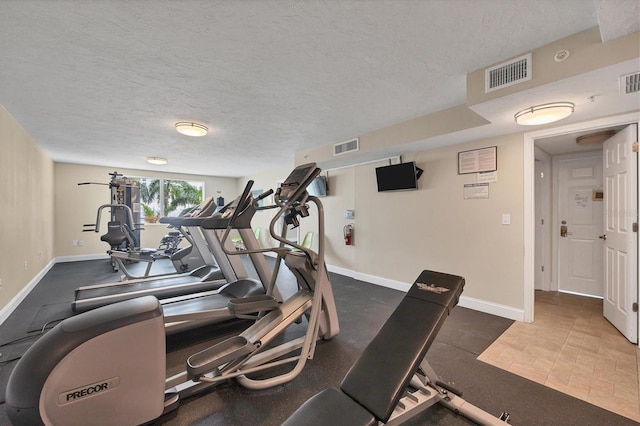 gym with a textured ceiling, visible vents, and baseboards