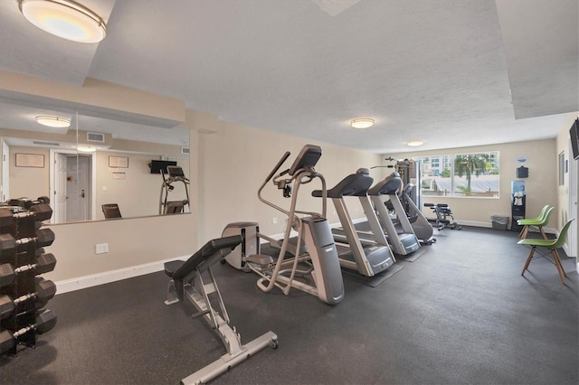 workout area featuring baseboards, visible vents, and a textured ceiling