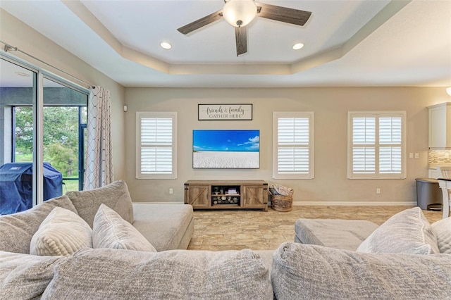 living room with a tray ceiling and ceiling fan