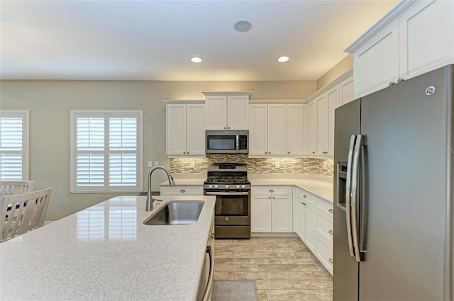 kitchen featuring sink, appliances with stainless steel finishes, white cabinetry, and decorative backsplash