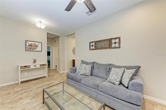 living room with a textured ceiling, ceiling fan, and light hardwood / wood-style floors