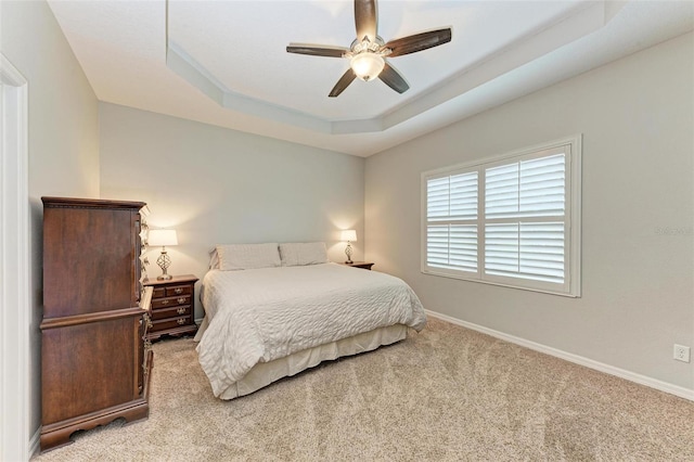 bedroom featuring a tray ceiling, ceiling fan, and light colored carpet