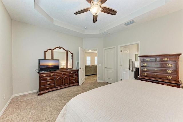 bedroom featuring a tray ceiling, light carpet, and ceiling fan