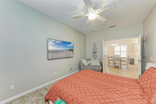 bedroom featuring a textured ceiling, ceiling fan with notable chandelier, and light wood-type flooring