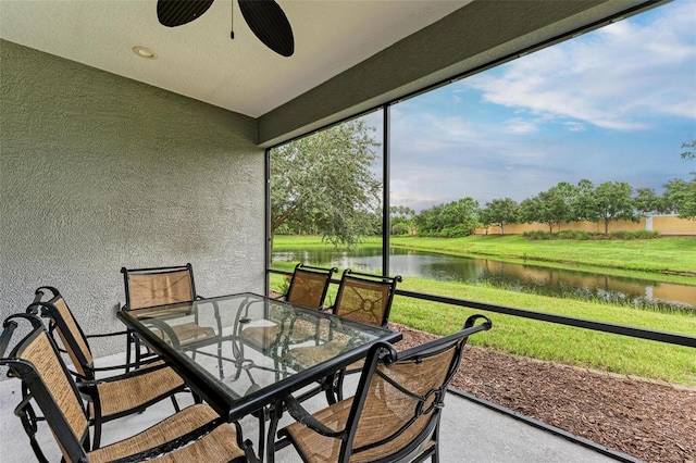 sunroom featuring ceiling fan and a water view