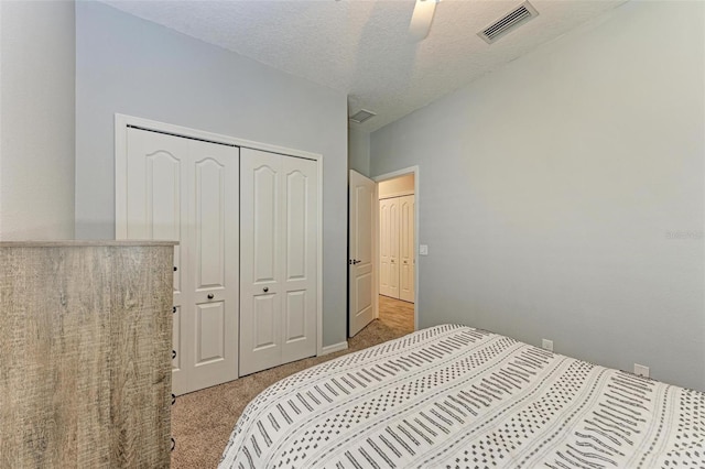 carpeted bedroom with a textured ceiling, ceiling fan, and a closet