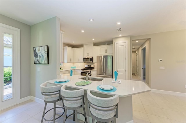 kitchen featuring sink, light tile patterned floors, a breakfast bar area, white cabinetry, and stainless steel appliances