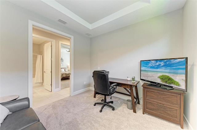 office with a tray ceiling and light carpet