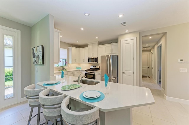 kitchen featuring light tile patterned flooring, sink, a breakfast bar area, stainless steel appliances, and white cabinets