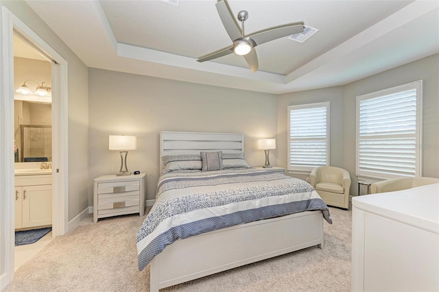 carpeted bedroom featuring a raised ceiling, ceiling fan, and ensuite bathroom