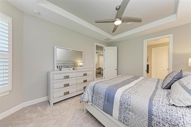 carpeted bedroom with ceiling fan, a textured ceiling, and a tray ceiling