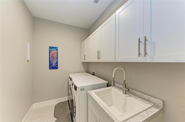 washroom featuring separate washer and dryer, sink, light tile patterned floors, and cabinets