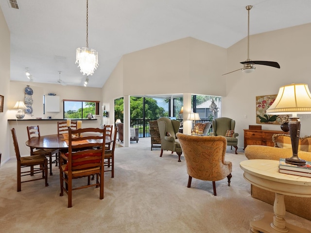 carpeted dining space with high vaulted ceiling and ceiling fan with notable chandelier