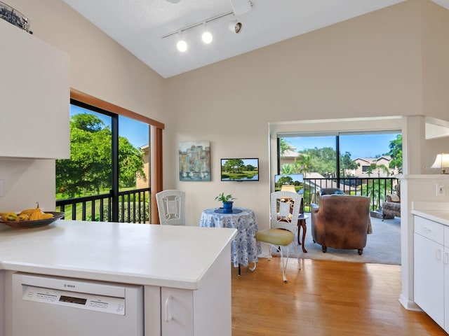 kitchen with lofted ceiling, dishwasher, light wood-type flooring, white cabinetry, and a textured ceiling