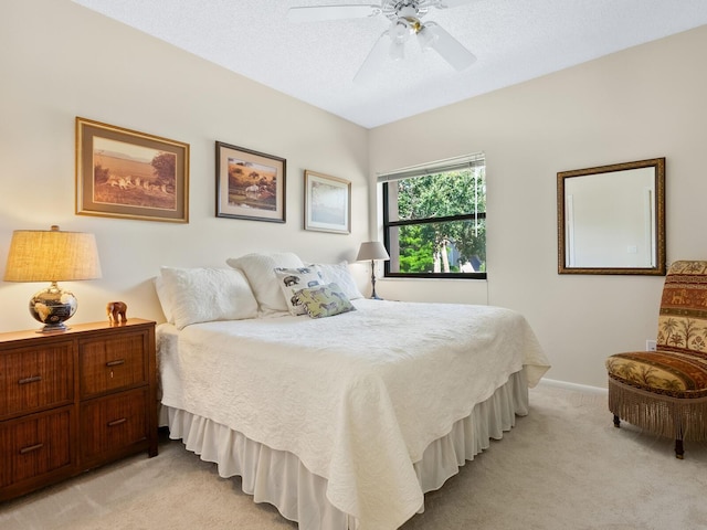 bedroom featuring ceiling fan, light carpet, and a textured ceiling